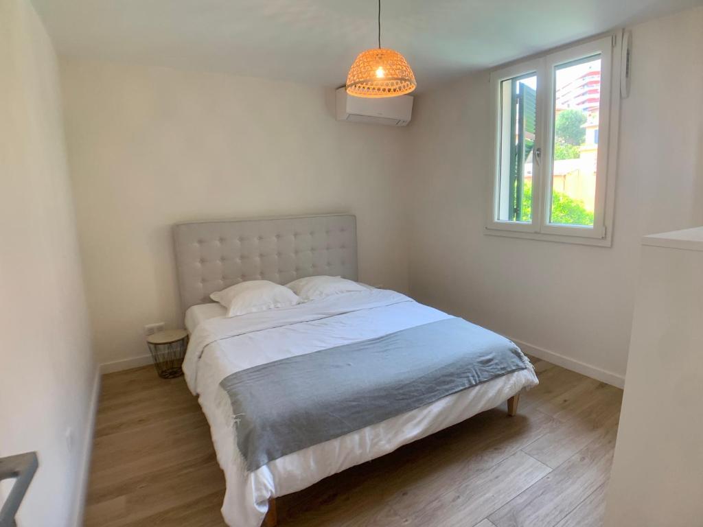 biała sypialnia z łóżkiem i oknem w obiekcie Appartement Monaco Larvotto PLAGE w mieście Roquebrune-Cap-Martin
