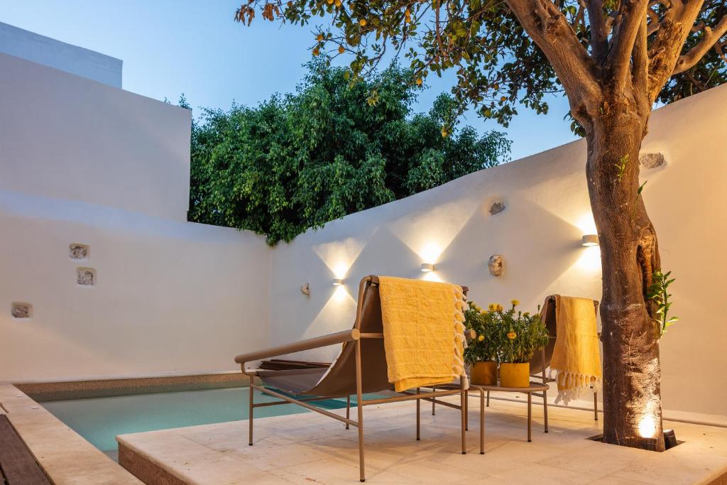 a pair of chairs and a tree next to a swimming pool at Villa Lemonia in Rethymno Town
