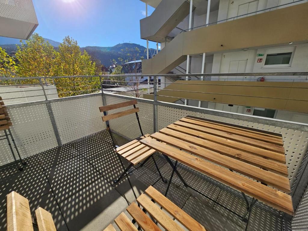 Stylish Apartment in Innsbruck + 1 parking spot في إنسبروك: مقعد خشبي فوق شرفة