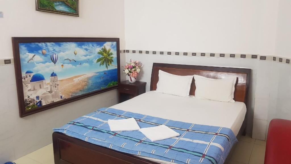 1 dormitorio con 1 cama con una pintura en la pared en Khách sạn Hoàng Long, en Ho Chi Minh