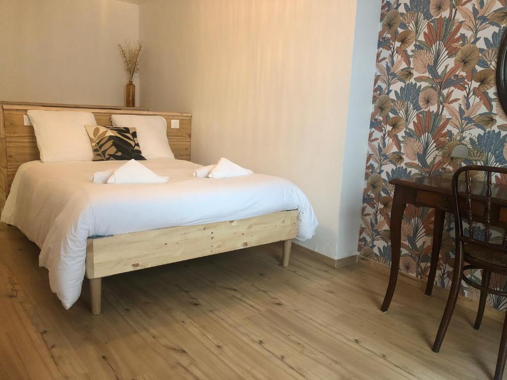 um quarto com uma cama com lençóis brancos e uma secretária em Chez SAM em Langres