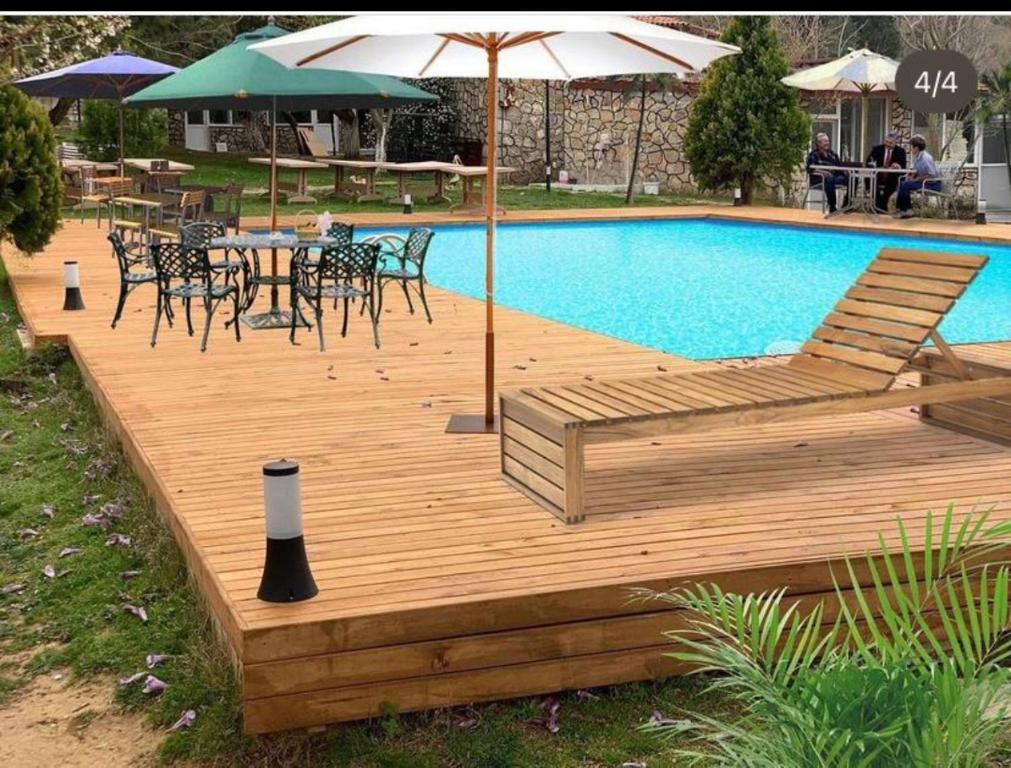 een houten terras naast een zwembad met een tafel en stoelen bij FAMİLY MOTEL RESTAURANT in Mecidiye