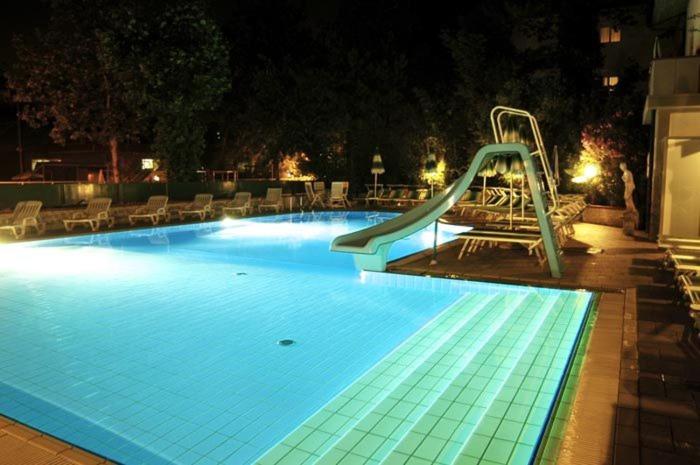 a swimming pool at night with a slide in it at Hotel Giamaika in Cesenatico
