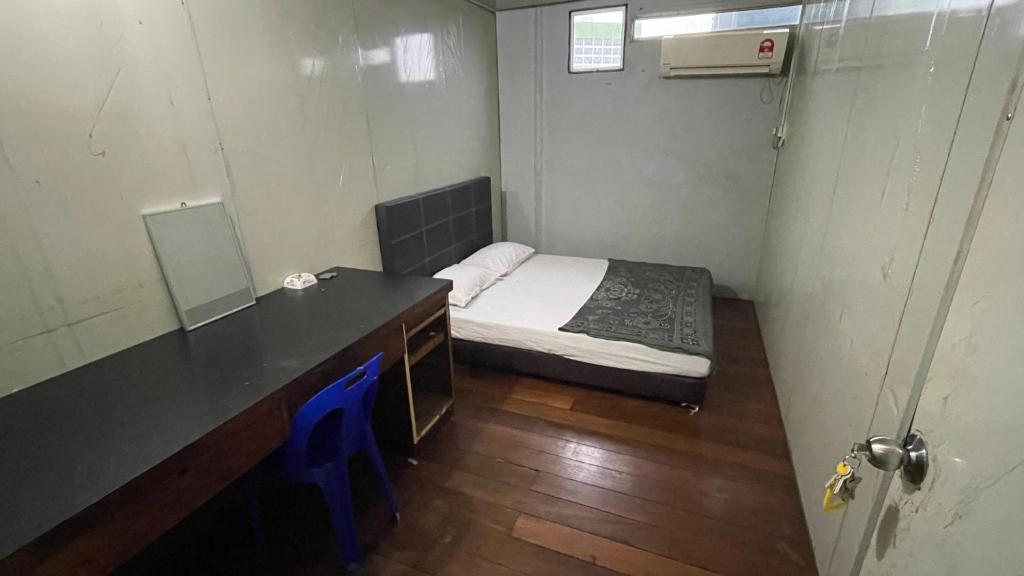 Habitación pequeña con cama y escritorio con espejo. en HOTEL 59, en Sibu