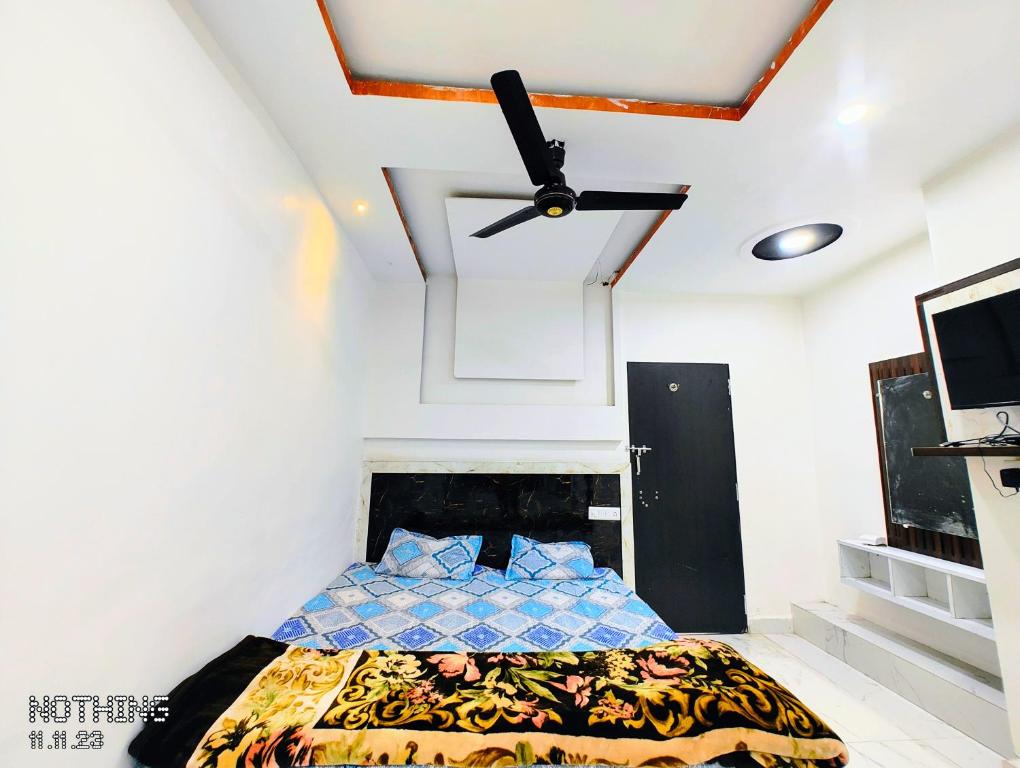 a bedroom with a bed and a ceiling fan at Hotel Unnat Shree. in Pachmarhī