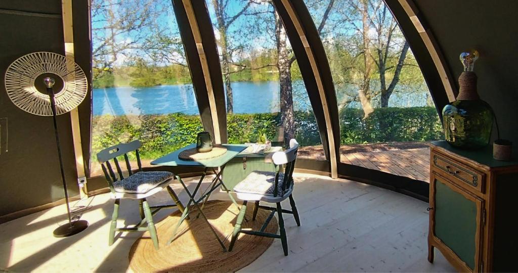 Habitación con mesa, sillas y ventana grande. en Bulle de l'étang - Etat Nature en Magnières