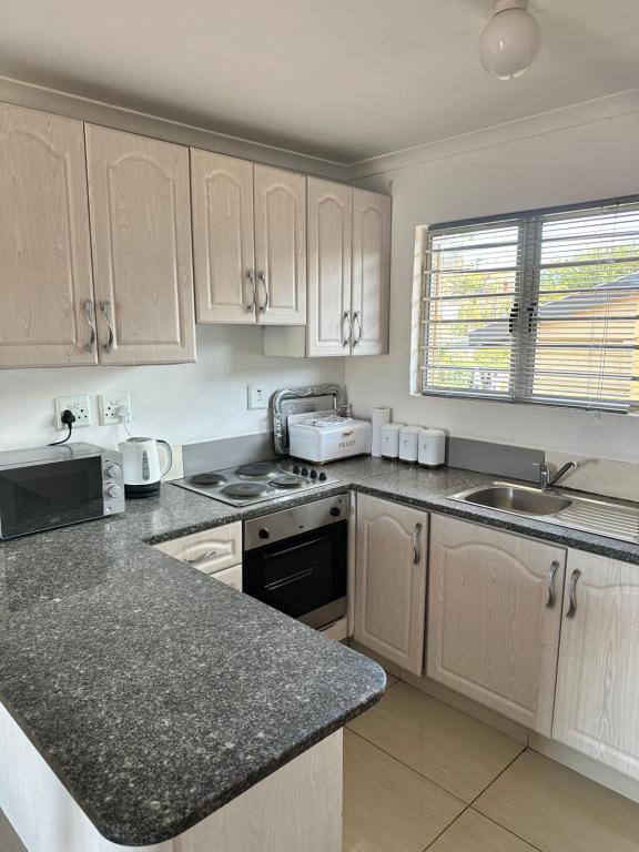 a kitchen with white cabinets and a black counter top at Wood Road Apartments in Durban