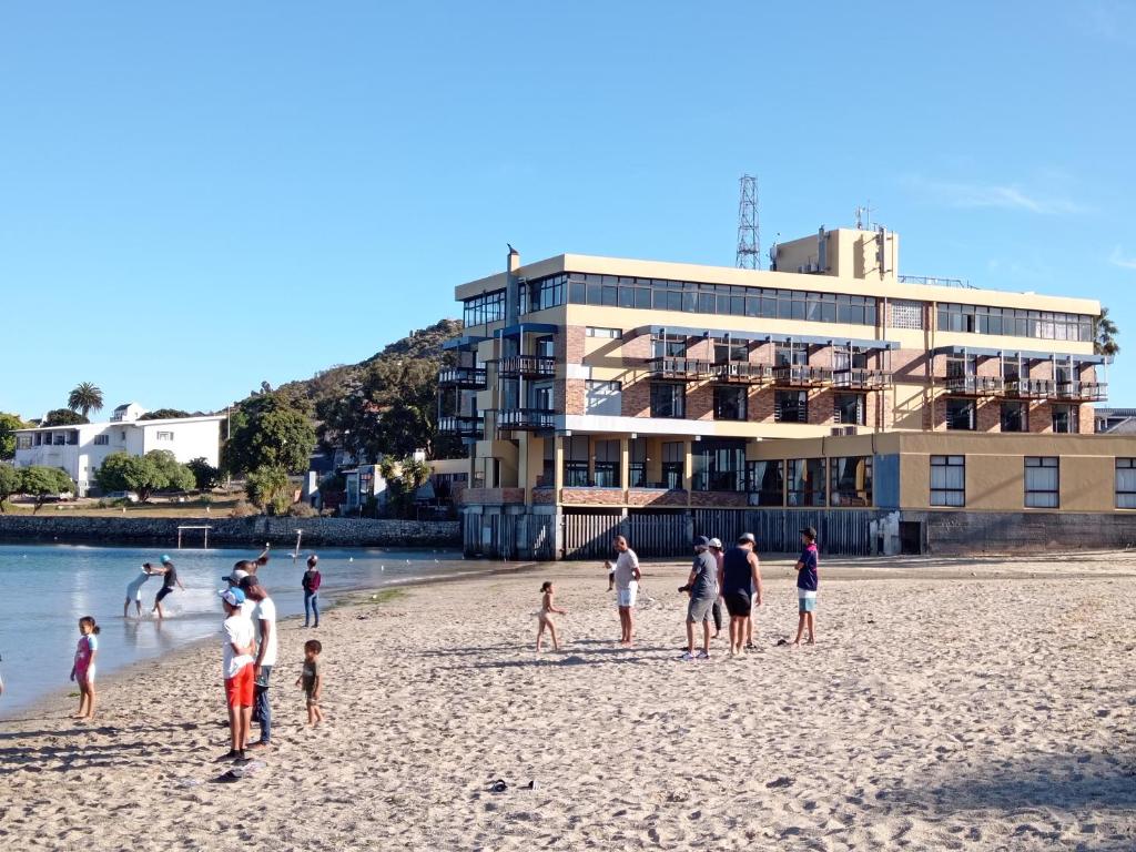 Hoedjiesbaai Hotel في سالدانها: مجموعة من الناس تقف على الشاطئ