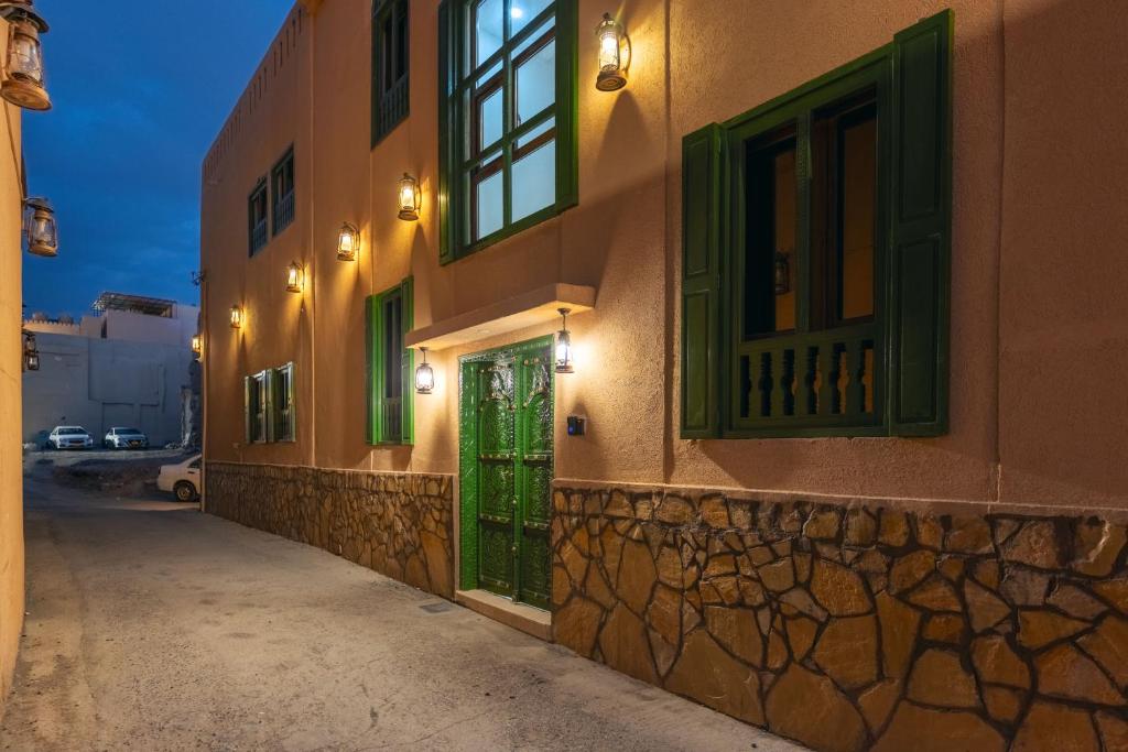 a building with green doors and windows on a street at House 76 in Nizwa