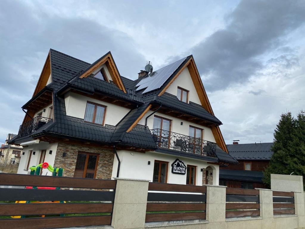 a house with a black roof on top of it at DW Na Równi Białka Tatrzańska in Białka Tatrzanska