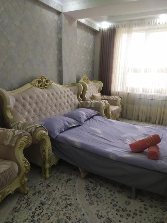 a bedroom with a bed and a couch and a window at 1комнатная квартира in Bishkek