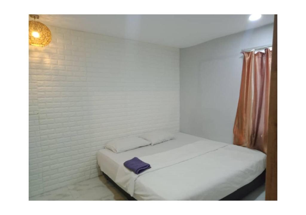 a white bedroom with a bed with a purple towel on it at EXPRESS OYO HOTEL in Kuala Lumpur