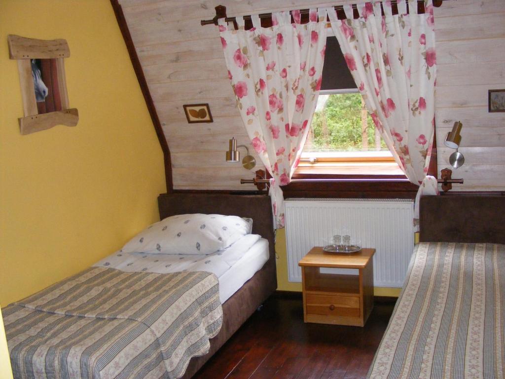 Cozy twin room with floral curtains, bedside table holding glasses, warm yellow walls.