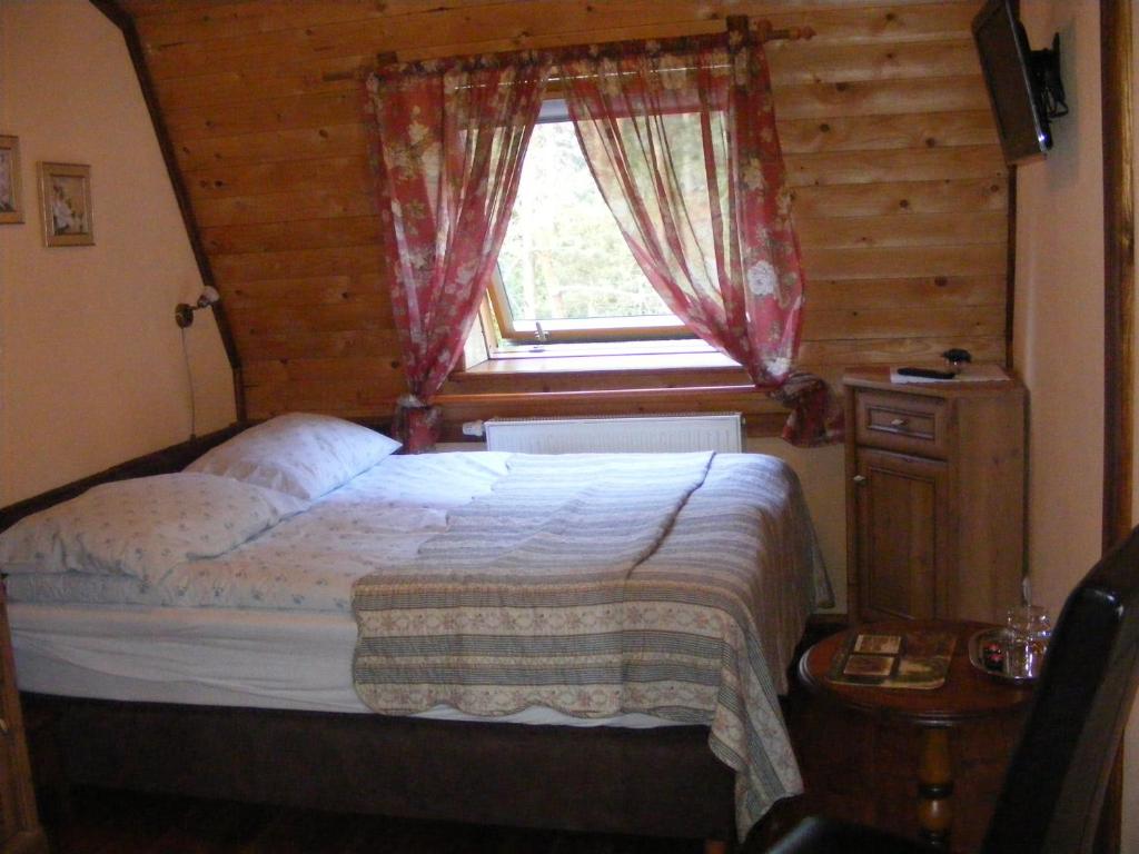 Cozy attic bedroom with double bed under skylight, floral curtains, wooden furniture, warm ambiance.