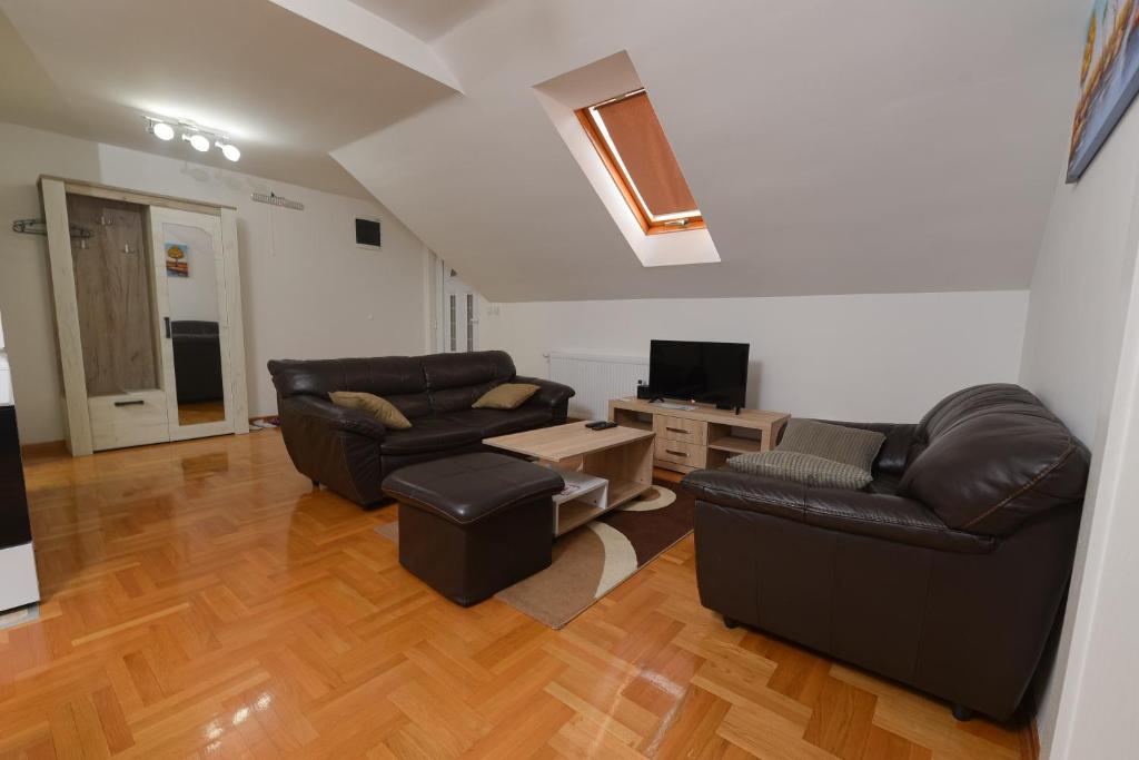 Sala de estar con 2 sofás de cuero y TV en Capitol Apartmani en Vrnjačka Banja