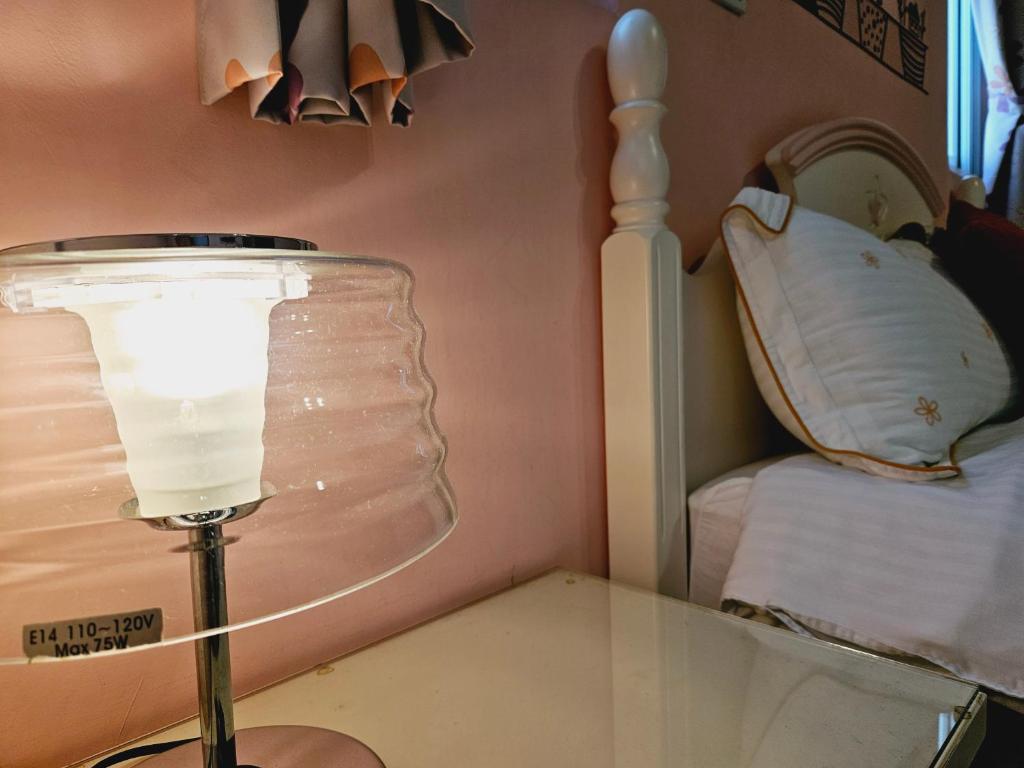 a glass table with a lamp next to a bed at Sunny Sun B&amp;B in Taitung City