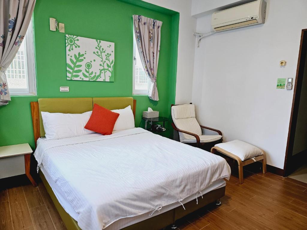 a bedroom with a bed with a green wall at Sunny Sun B&amp;B in Taitung City
