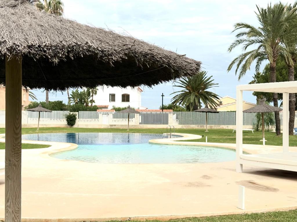 una piscina con sombrilla y palmeras en Apartamento La Calma a 2 pasos de la playa, en Denia