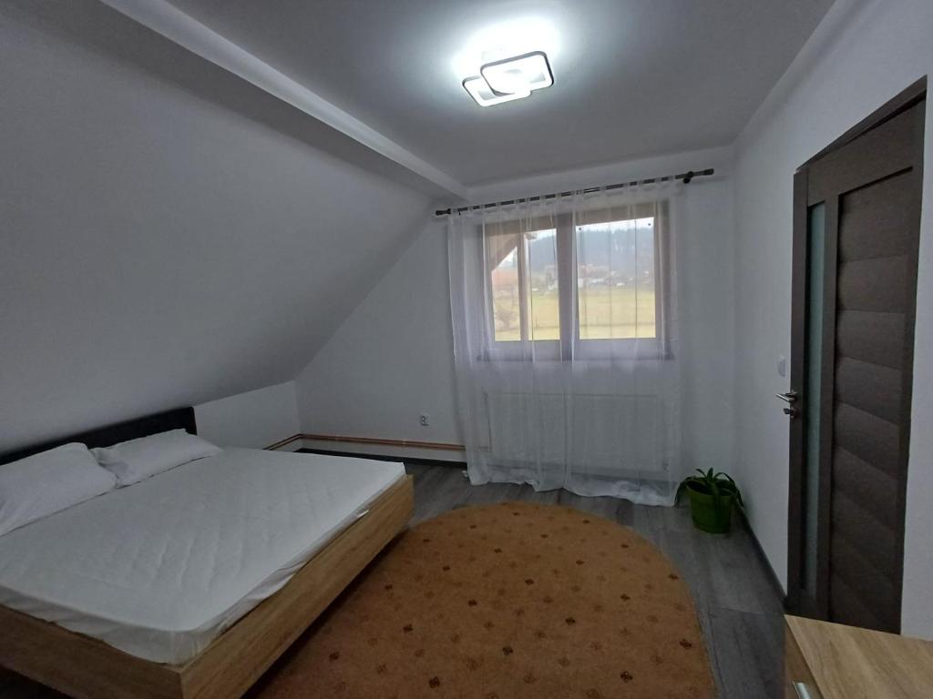 a bedroom with a bed and a window and a rug at Casa Alex in Gălăuţaş