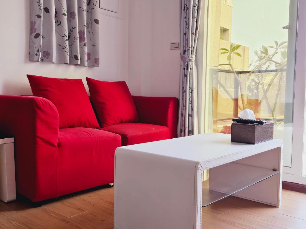 a living room with a red couch and a white table at Sunny Sun B&amp;B in Taitung City