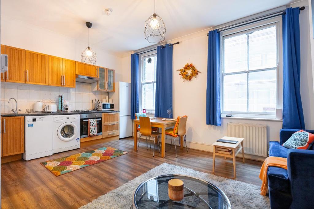 a kitchen and a living room with a table and chairs at Lovely One Bed in the Heart of Covent Garden in London