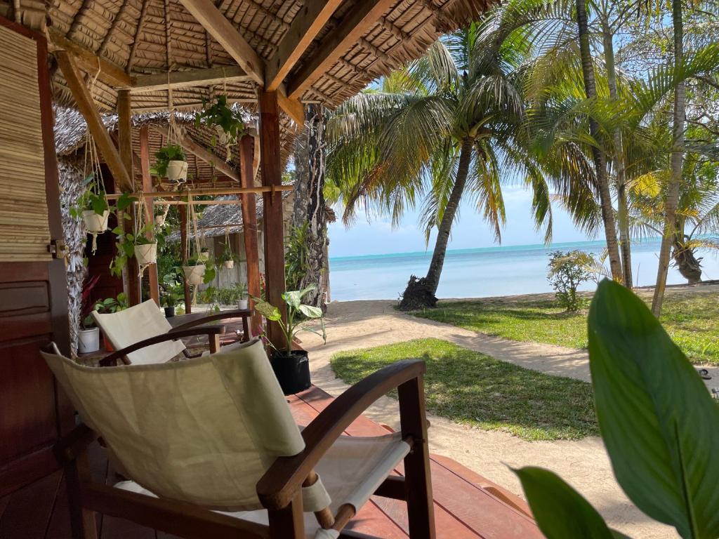 a porch with a chair and a view of the beach at Aurora Lodge in Ile aux Nattes