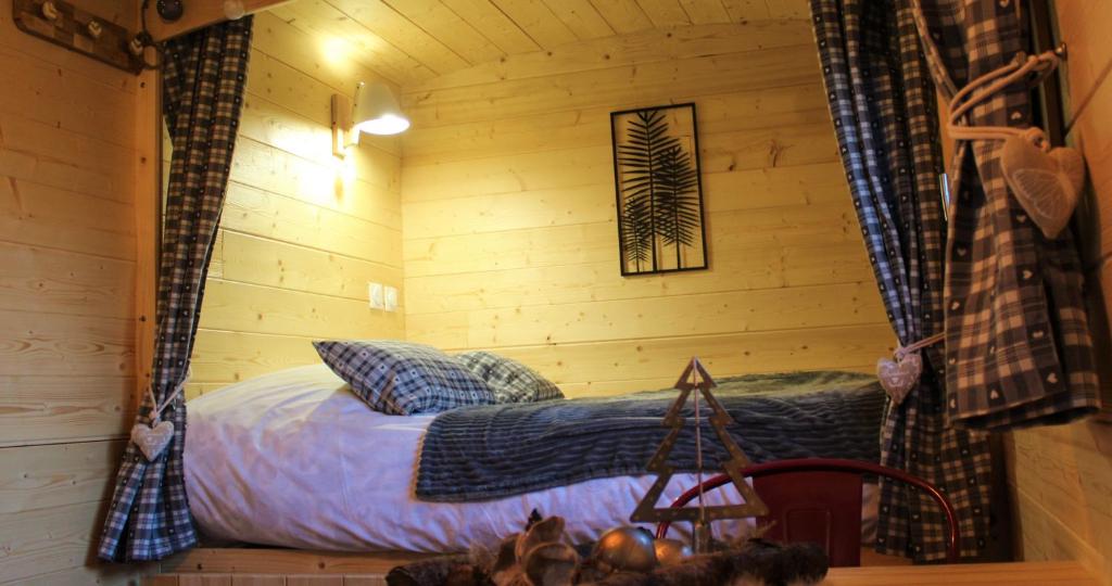 a bed in a log cabin with curtains in a room at Roulotte - Etat Nature in Magnières