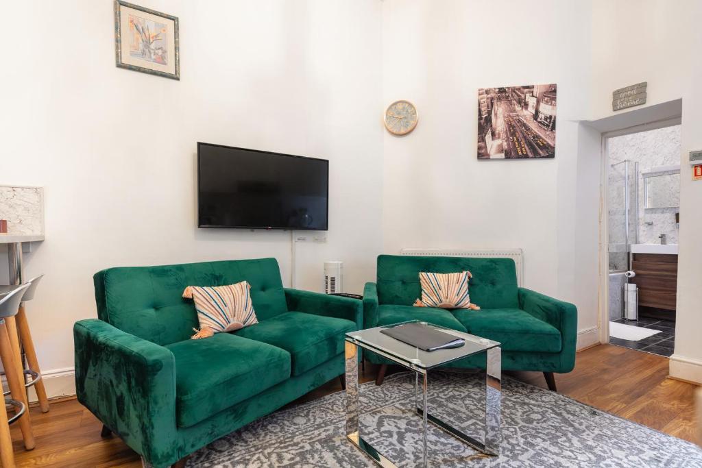 a living room with two green couches and a tv at DELUXE Two Bed in Covent Garden in London