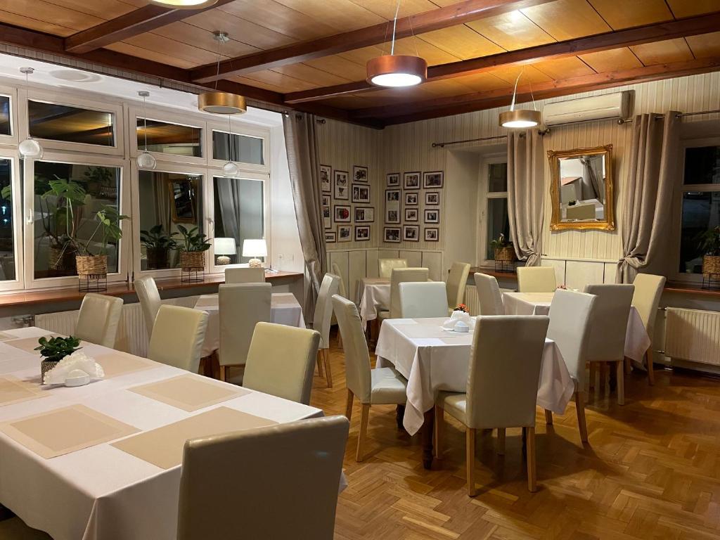 un restaurante con mesas y sillas blancas y ventanas en Hotel SONATA en Duszniki Zdrój