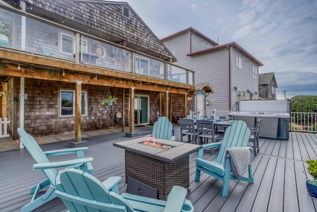 una terraza con sillas, mesas y una parrilla en Chinook Overlook, en Lincoln City