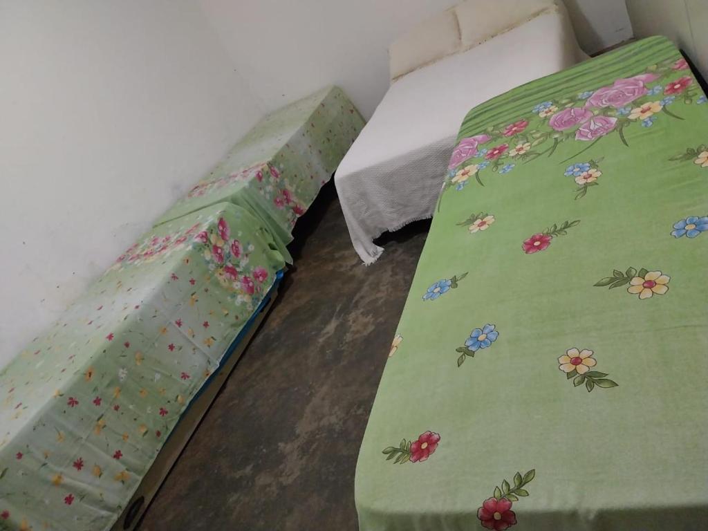 a bed with a green bedspread with flowers on it at Hospedagem Santa Gertrudes Comensoli in Cachoeira Paulista