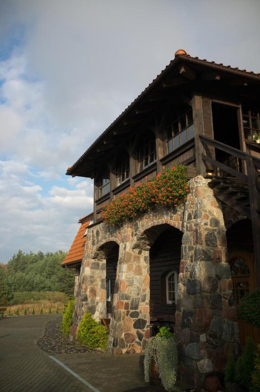 Stone-arched lodge exterior with balcony, wooden accents and window boxes of orange flowers.