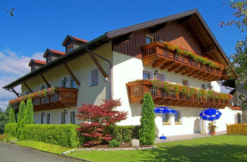 Pension Lichtenauer Hof في Thyrnau: مبنى عليه شرفات خشبية وورود