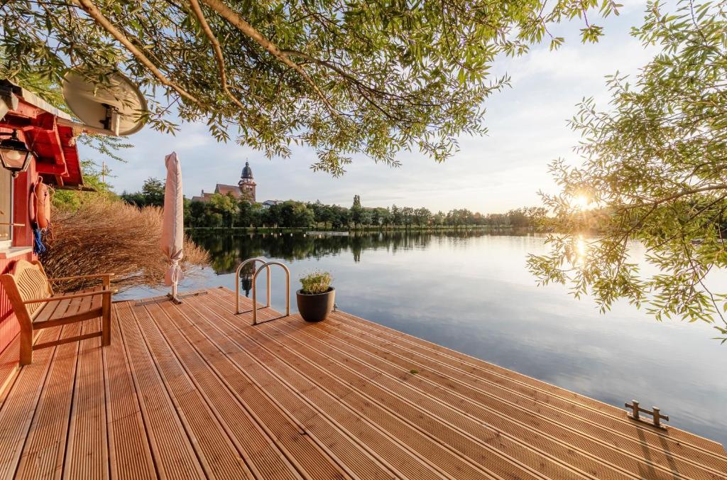 ein Holzsteg mit einer Bank auf einem See in der Unterkunft SeeAuszeit am Tiefwarensee in Waren (Müritz)