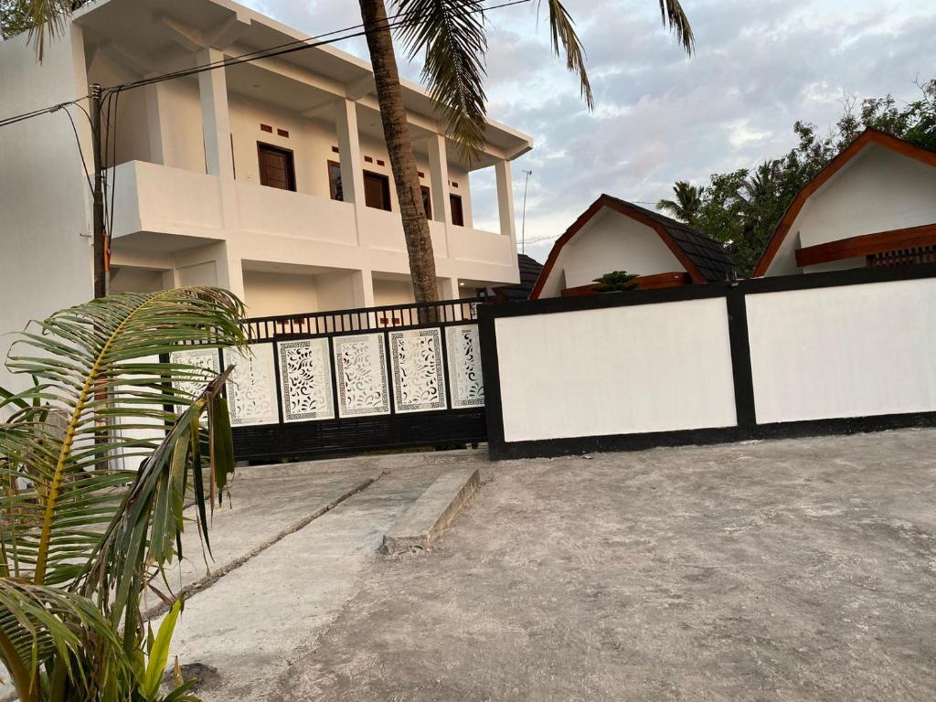 a house with a black and white fence at Linobi Homestay in Sengkol