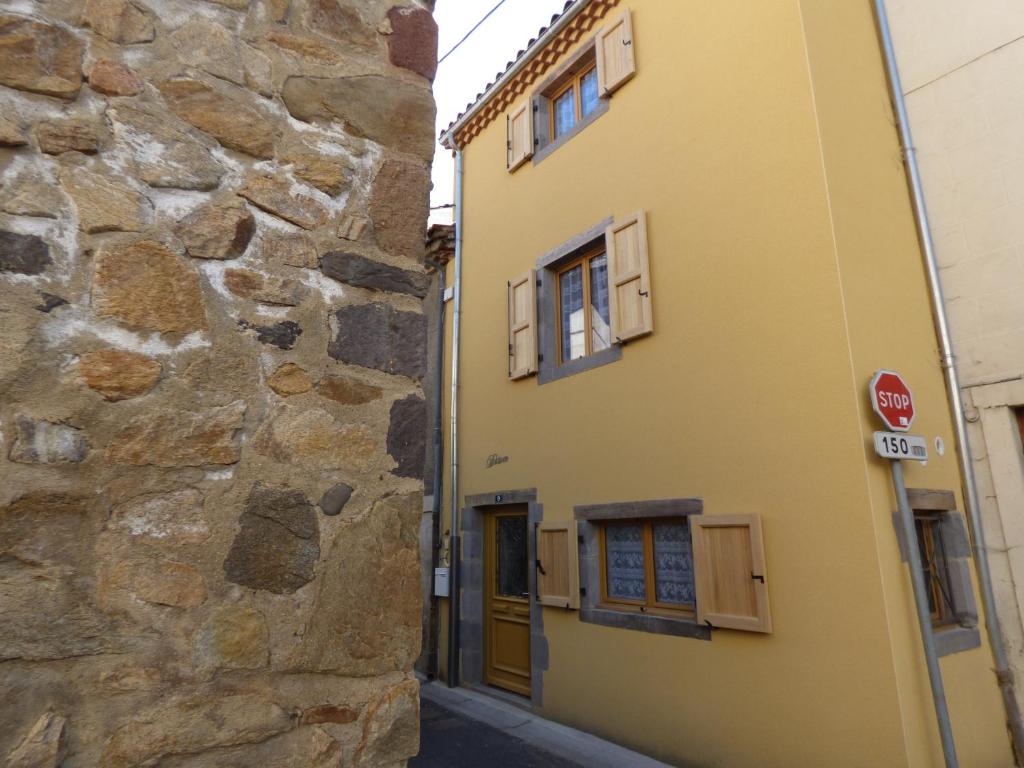 un bâtiment jaune à côté d'un mur en pierre dans l'établissement Désirée, à Brioude