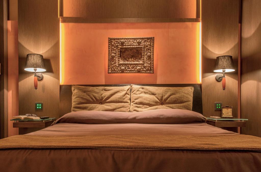 a bedroom with a large bed with two lamps at Hotel Capo San Vito by Geocharme in San Vito lo Capo