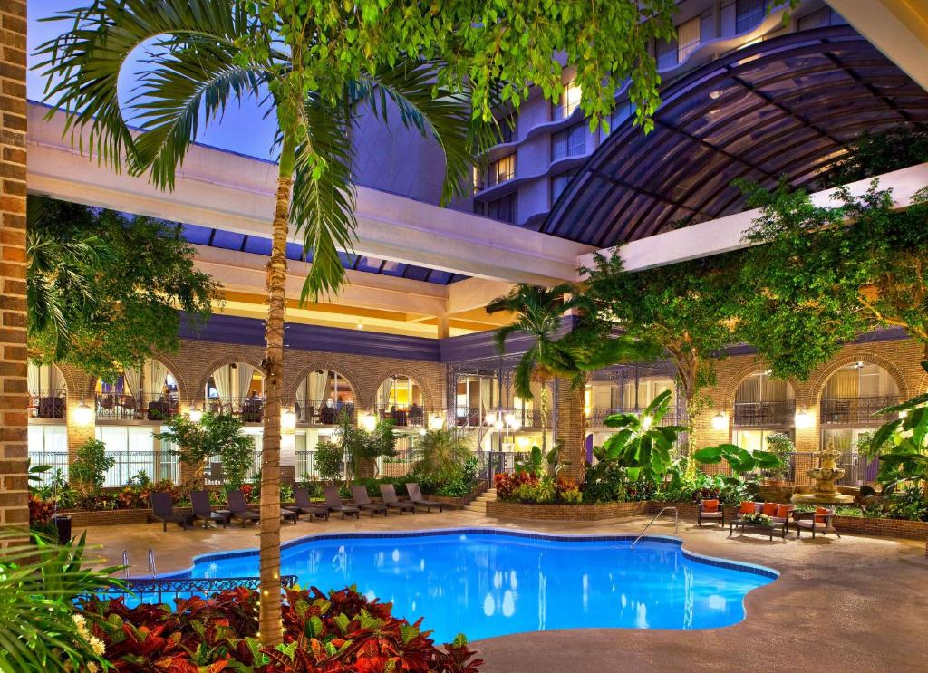 a hotel lobby with a large pool and palm trees at Courtland Grand Hotel, Trademark Collection by Wyndham former Sheraton Atlanta in Atlanta