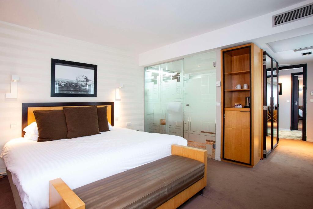 a bedroom with a large white bed and glass walls at Hotel Lille Euralille - Hilton Affiliate Hotel in Lille