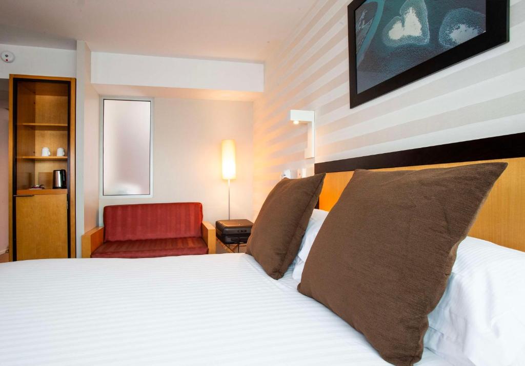 a hotel room with a bed and a red chair at Hotel Lille Euralille - Hilton Affiliate Hotel in Lille