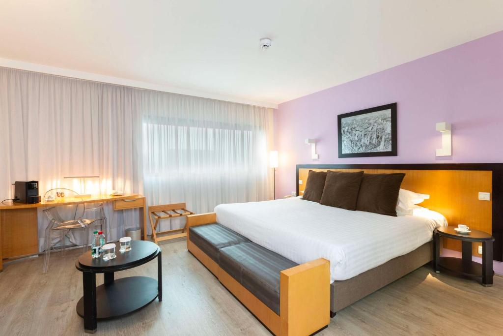 a hotel room with a large bed and a table at Hotel Lille Euralille - Hilton Affiliate Hotel in Lille