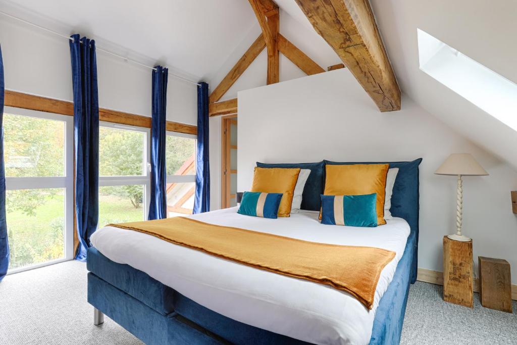 a bedroom with a large bed with blue and orange pillows at La Rivière 10 mn DisneylandParis in Chalifert