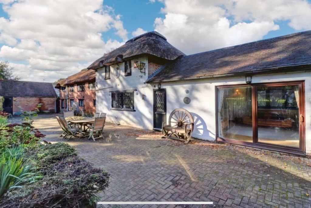 a white cottage with a thatched roof and a patio at Reads Cottage in Waterlooville