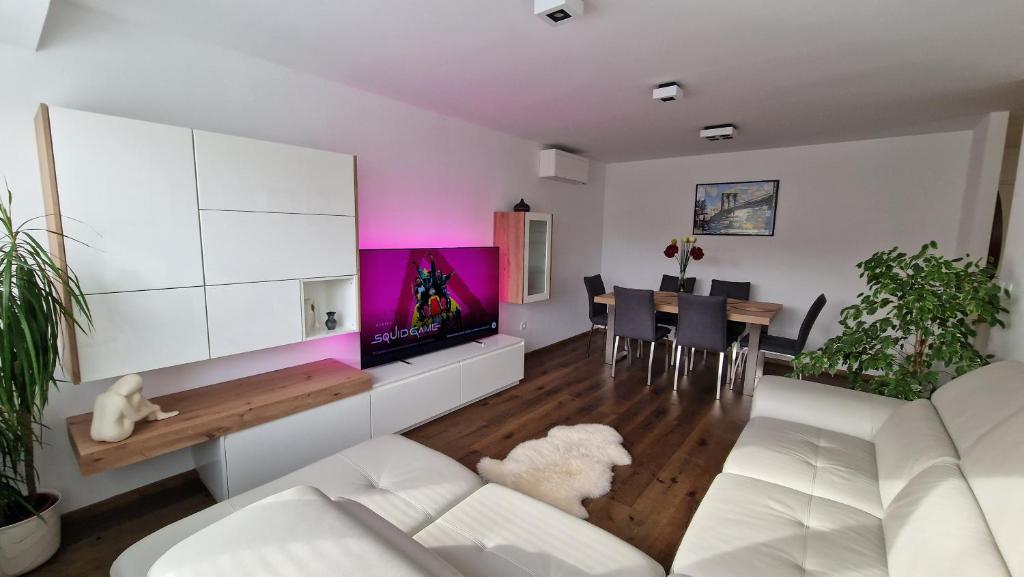 a living room with a white couch and a tv at Apartma VAL in Maribor