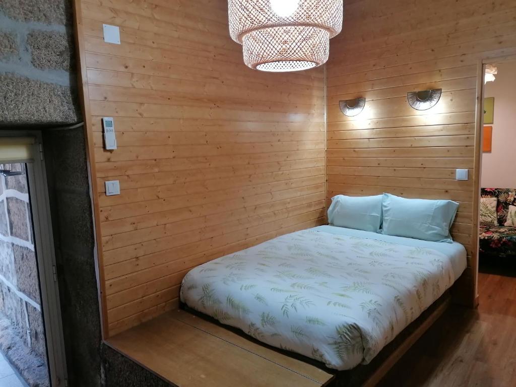 a bed in a wooden walled room at Era Uma Vez Apartment in Vila Real