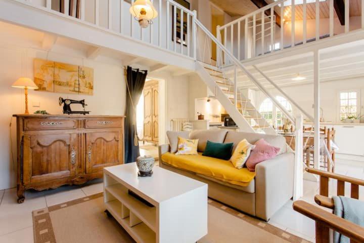 a living room with a yellow couch and a staircase at LE GITE du REFUGE du PEINTRE proche de St Emilion in Sainte-Terre