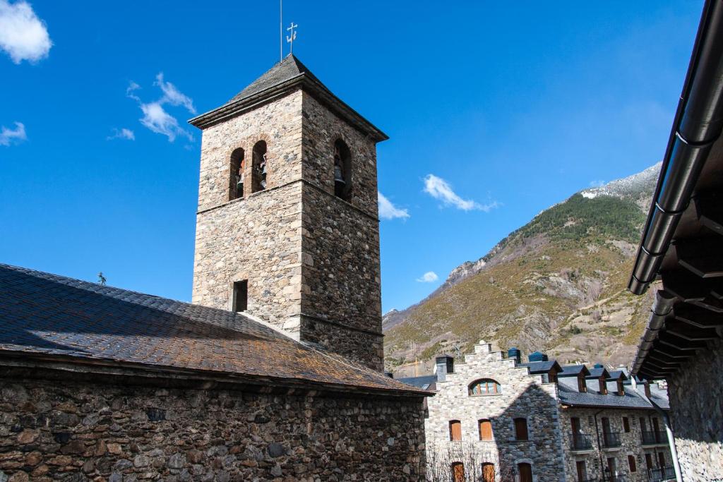 an old stone building with a tower in front of a mountain at Casa Chuanina in Benasque