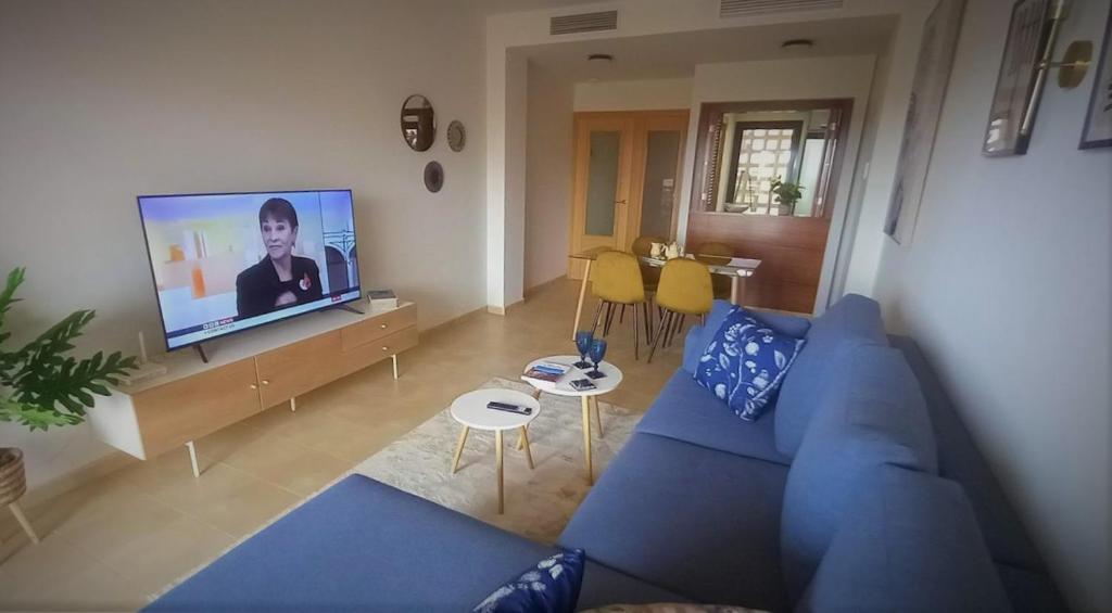 ein Wohnzimmer mit einem blauen Sofa und einem Flachbild-TV in der Unterkunft Casa Martinica 12-1-A , Hacienda del Alamo in Murcia
