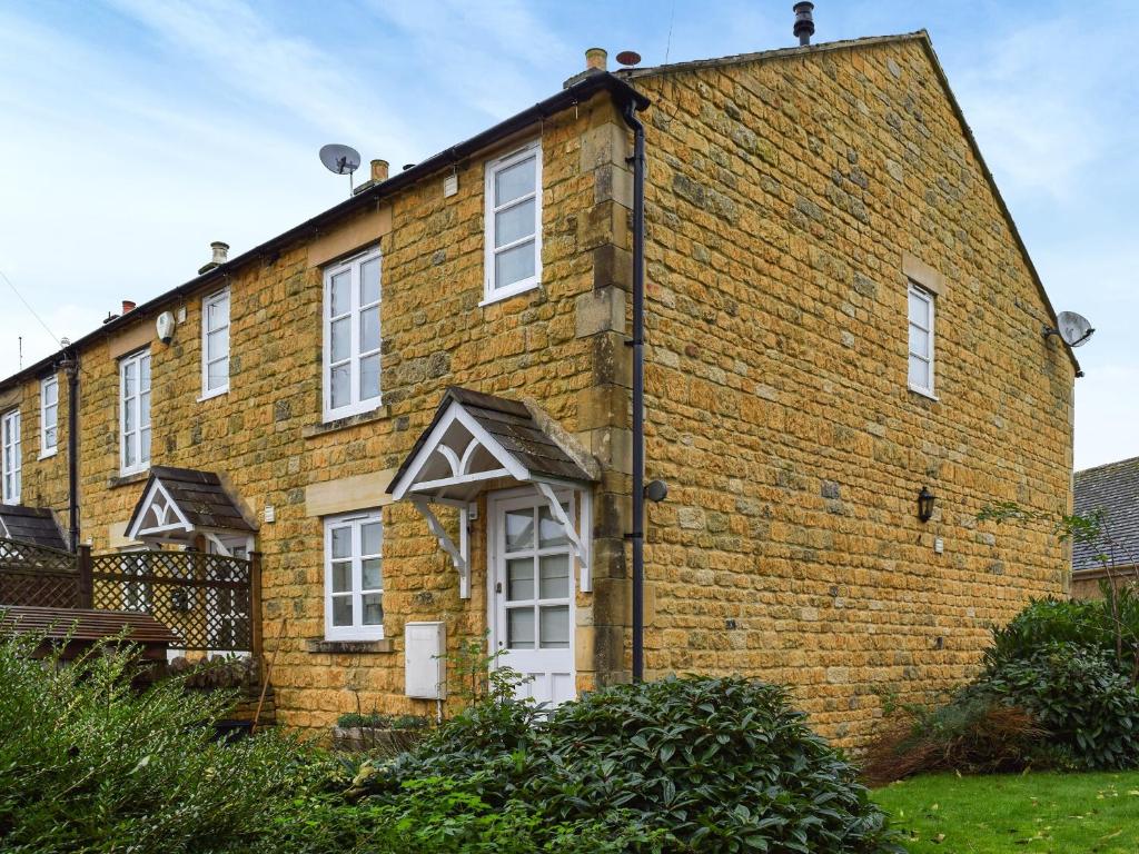 an old brick building with white windows on it at Bea Cottage in Bourton on the Water