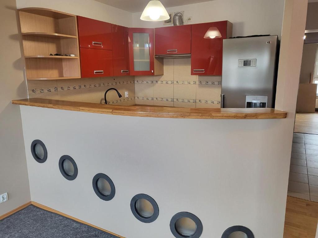 una cucina con armadi rossi e frigorifero in acciaio inossidabile di 2 pokojowy apartament a Stettino